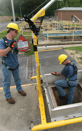 two workers use fall protection PPE to climb into a hole