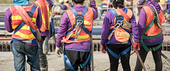four workers in safety vest and fall protection harness