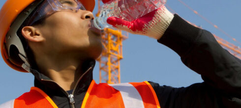 employee wearing safety vest drinking an electrolyte water
