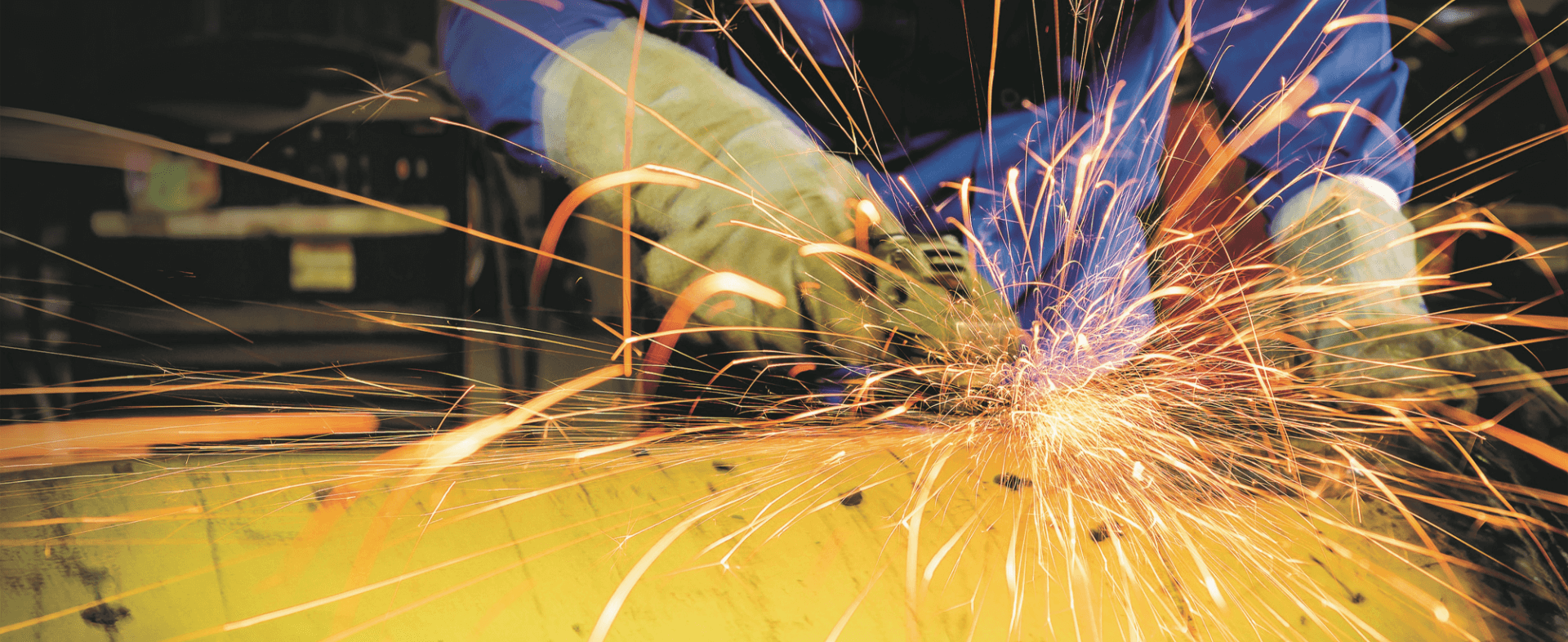 Worker cutting metal as sparks fly