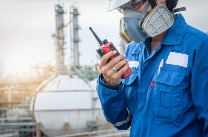 technician with gas mask against petrochemical plant