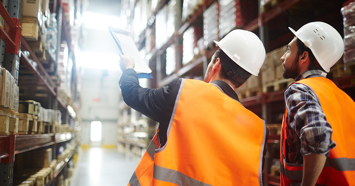 Safety director in warehouse pointing at inventory