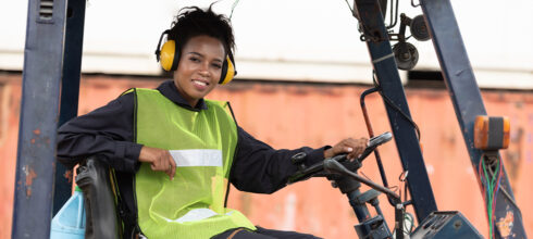 woman in forklift wearing safety vest and ear protection