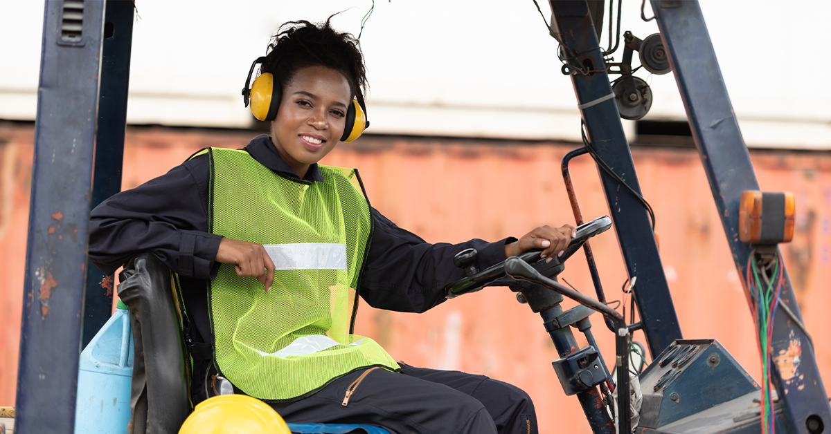 woman in forklift wearing safety vest and ear protection