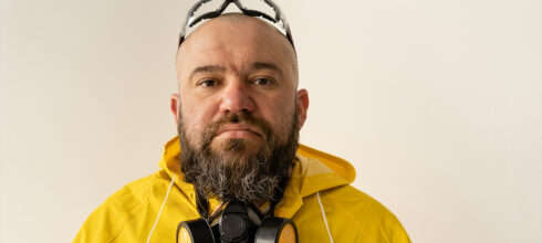 Man with beard wearing a respirator, safety glasses and yellow hazmat suit