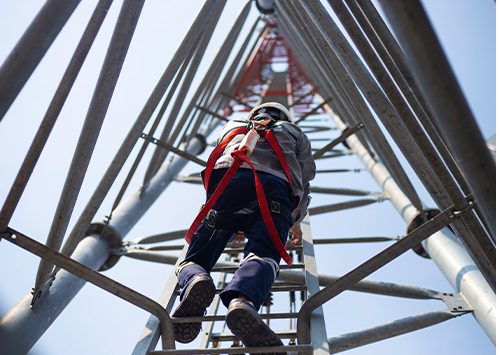 safety worker with harness and hard hat climbing up pole ladder