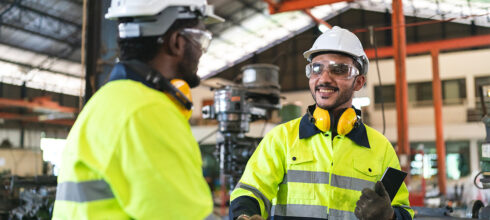 safety manager in ppe shaking hands with warehouse worker