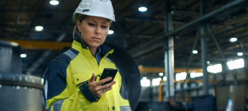 female safety worker in hi-vis ppe and hard hat looking at mobile phone