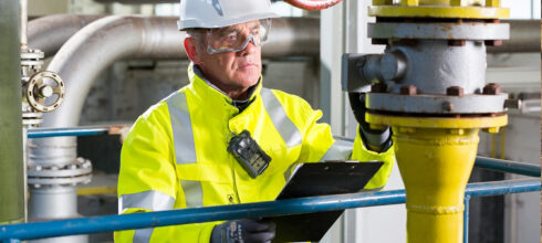 safety worker wearing hard hat and ppe holding clipboard