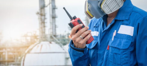 Employee wearing respiratory PPE outide construction site using safety equipment