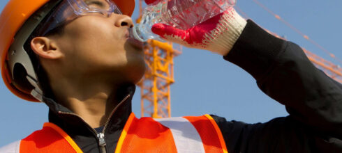 employee wearing safety vest drinking an electrolyte water