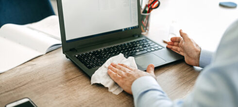 person using wipe to clean laptop computer