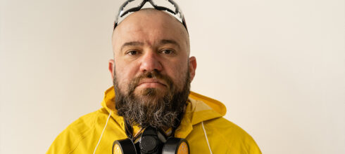 Man with beard wearing a respirator, safety glasses and yellow hazmat suit