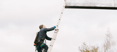 Billboard installer climbing ladder at height