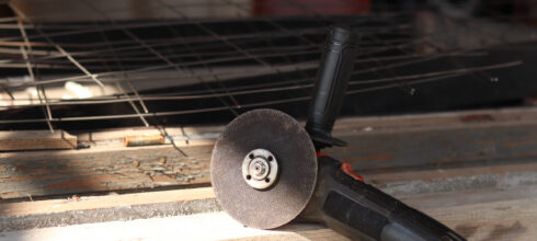 An angle grinder with a worn cutting disc resting on a wooden workbench, symbolizing the importance of replacing tools before wear affects performance.